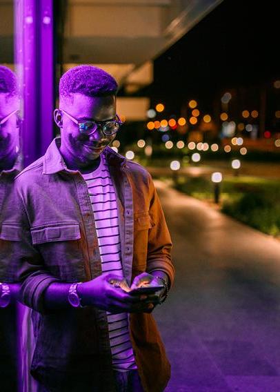 Young Black man in glasses looks down at a cellphone